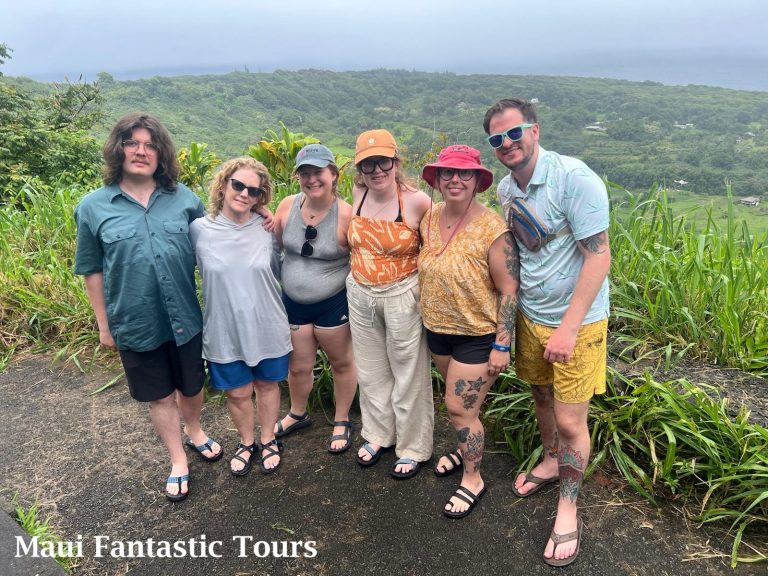 Happy group of tourists posing at a lush green mountain view during a Maui Fantastic Tours trip